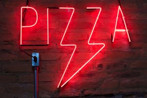 Pizza neon sign on a brick wall